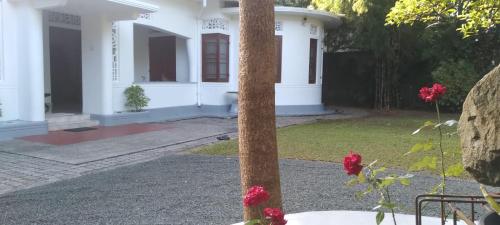 a white house with red flowers in front of it at Crescent N Cocoon in Ambalangoda
