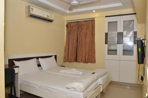 a bedroom with a white bed and a window at Da Casa Business Hotel in Pune