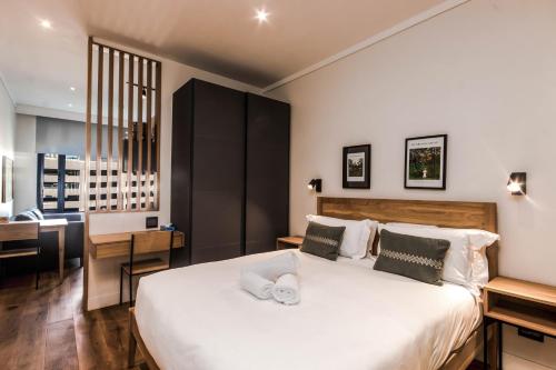 a bedroom with a large white bed and a desk at The Barracks Apartments in Cape Town