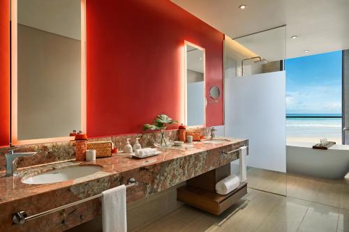 a bathroom with a sink and a mirror and a tub at Angsana Quan Lan, Ha Long Bay in Quan Lạn