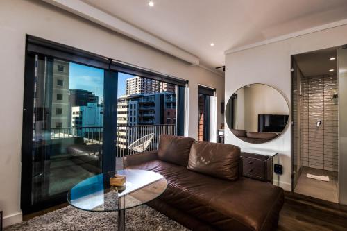 a living room with a leather couch and a mirror at The Barracks Apartments in Cape Town