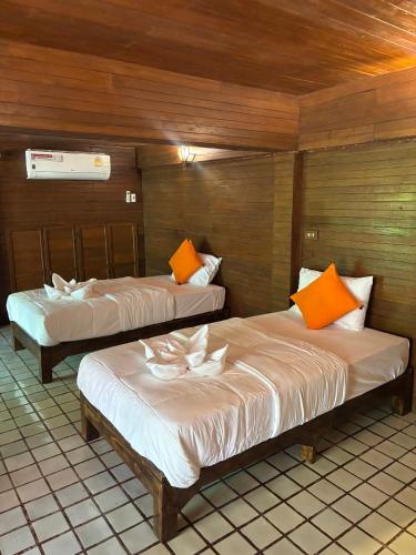 two beds with orange and white pillows in a room at Stay At Lantana Mae Rim in Ban Pa Muang