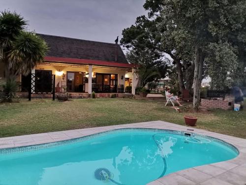 a swimming pool in front of a house at Cheetah Lodge Guest House in Hartenbos