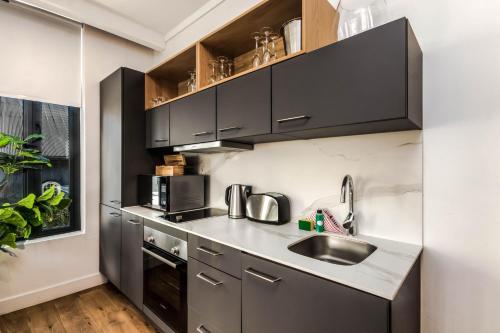 a kitchen with black cabinets and a sink at The Barracks Apartments in Cape Town