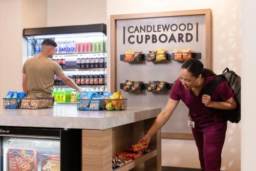 a woman is standing at a counter in a supermarket at Candlewood Suites Orange by IHG in Orange