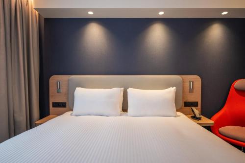 a bedroom with a white bed and a red chair at Holiday Inn Express & Suites Ghent by IHG in Ghent