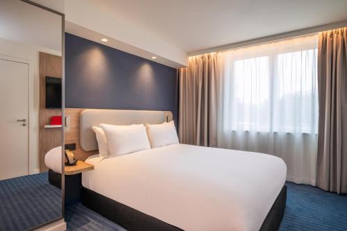 a bedroom with a white bed and a large window at Holiday Inn Express & Suites Ghent by IHG in Ghent
