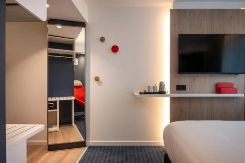 a hotel room with a bed and a tv and a mirror at Holiday Inn Express & Suites Ghent by IHG in Ghent