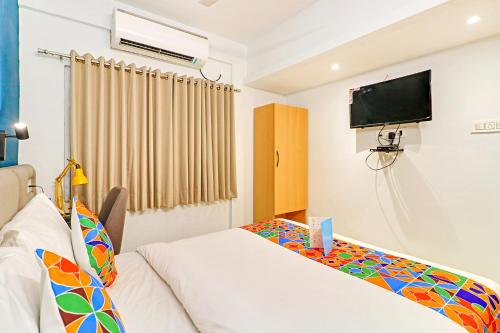a bedroom with a bed and a tv on the wall at FabHotel Azure Sky - Nr Ruby Hospital in Kolkata