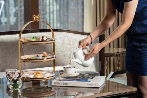 a woman pouring tea from a tea pot on a table at Fairmont Chengdu in Chengdu
