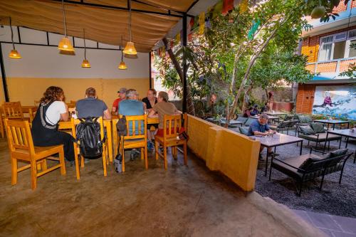 a group of people sitting at tables in a restaurant at Kwabahal Garden Hostel in Kathmandu