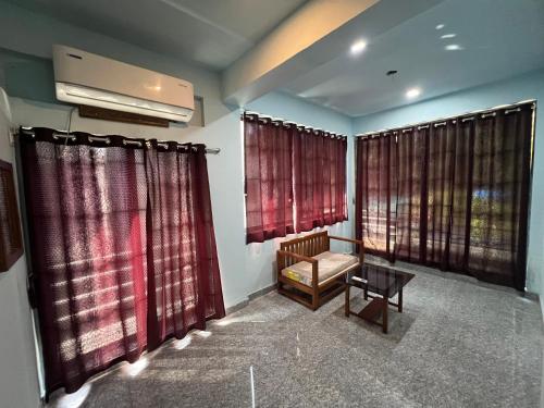 a living room with red curtains and a chair at Beach Side Home Stay - Kihim in Kīhīm