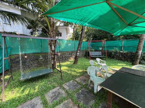 a patio with a swing set and a green umbrella at Beach Side Home Stay - Kihim in Kīhīm