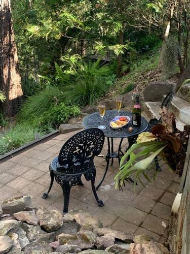 a table and chair with two glasses of wine at Williams River Retreat in Dungog