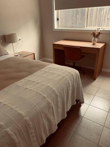 a bedroom with a desk and a bed with a bedspread at Williams River Retreat in Dungog
