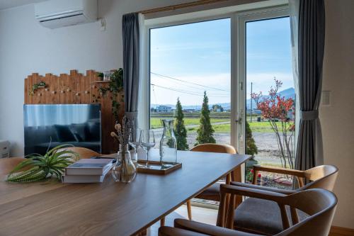 een eetkamer met een tafel en een groot raam bij Clematis in Nakafurano