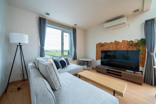 een woonkamer met een bank en een televisie bij Clematis in Nakafurano