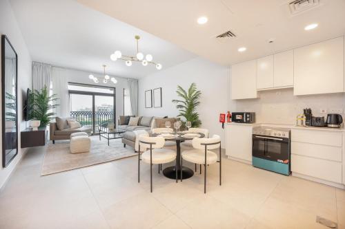 a kitchen and living room with a table and chairs at Free housekeeping visits during your stay - StayShort - Warm and Earthy 1-Bedroom Apartment Perfect for Family in Madinat Jumeirah Living! in Dubai
