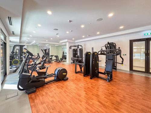 a gym with treadmills and cardio equipment in a room at Free housekeeping visits during your stay - StayShort - Warm and Earthy 1-Bedroom Apartment Perfect for Family in Madinat Jumeirah Living! in Dubai