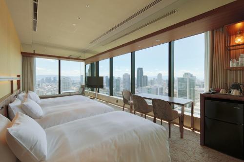 a hotel room with two beds and a desk and windows at Candeo Hotels Osaka The Tower in Osaka