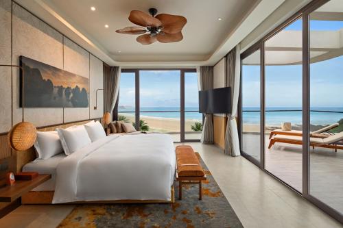a bedroom with a bed and a view of the ocean at Angsana Quan Lan, Ha Long Bay in Quan Lạn
