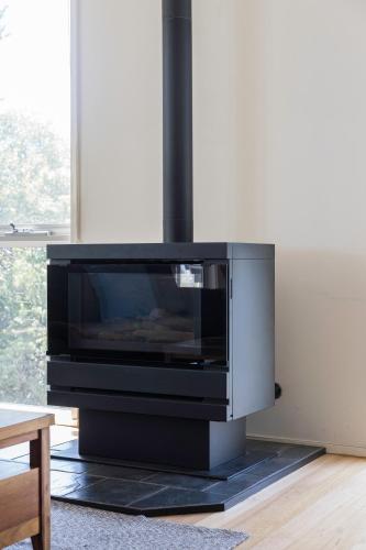 a tv sitting on a black stand in a living room at Treetop Tides - Scenic Tootgarook Coastal Getaway in Tootgarook