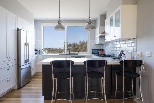 a kitchen with a large island with three bar stools at Treetop Tides - Scenic Tootgarook Coastal Getaway in Tootgarook