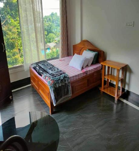 a bedroom with a bed with a table and a window at Rongo Hill View Homestay by StayApart in Kumai