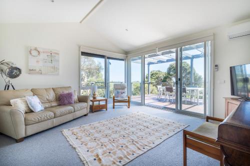 a living room with a couch and sliding glass doors at Treetop Tides - Scenic Tootgarook Coastal Getaway in Tootgarook