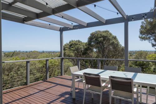 a wooden deck with a white table and chairs on it at Treetop Tides - Scenic Tootgarook Coastal Getaway in Tootgarook