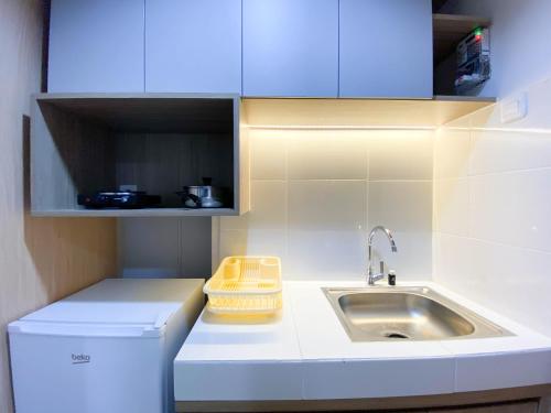 a small white kitchen with a sink and a counter at Comfort and Cozy Stay 1BR at The Alton Apartment By Travelio in Semarang