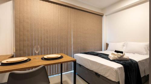 a bedroom with a bed and a table with two plates on it at By DH: Luxo e conforto em Perdizes, aos poucos minutos do Allianz parque in Sao Paulo