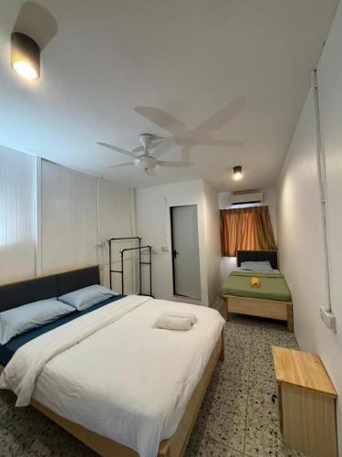 a bedroom with a large bed with a ceiling fan at 5 Minutes Airport Lodge in Kampong Patagas