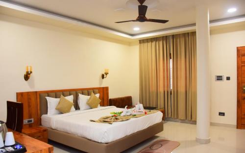 a bedroom with a large bed and a desk and a ceiling fan at Hotel Royal Palace in Sāgar