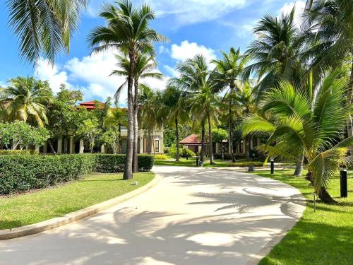 a street with palm trees in front of a house at Laguna Village by RESAVA in Layan Beach
