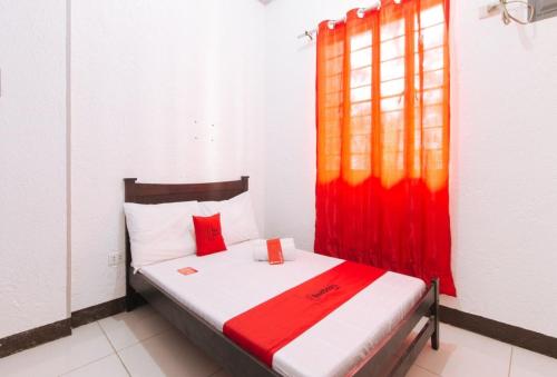 a bedroom with a bed with a red curtain at RedDoorz Plus near Tambo Paranaque in Manila