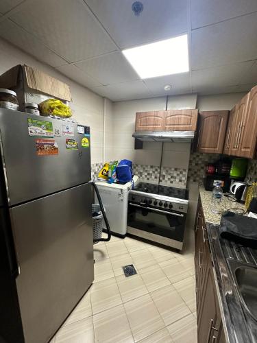 a kitchen with a stainless steel refrigerator and a stove at RG's Home 2, Men Bedspace in Sharjah