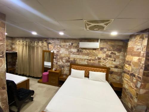 a bedroom with a bed and a stone wall at Hotel Vista Inn DHA in Rawalpindi