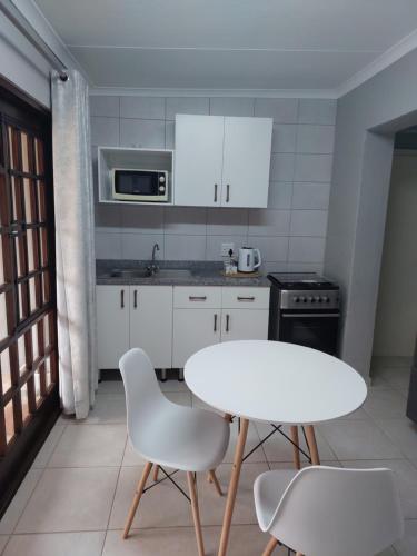 a white kitchen with a white table and chairs at Fairway Guest Lodge in Margate