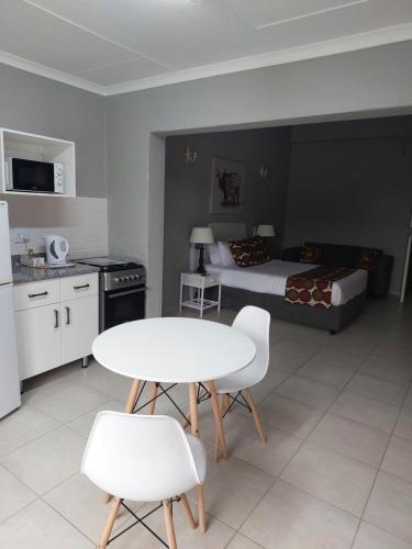 a room with a bed and a white table and chairs at Fairway Guest Lodge in Margate