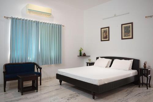 a bedroom with a bed and a blue chair at Casa Romana- Indulgent Comfort in Lake and Hill View Rooms in Udaipur