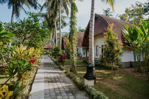 a walkway in front of a house with palm trees at Crystal Bay Villa in Nusa Penida