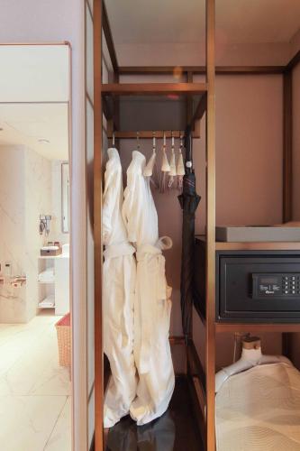a closet with white dresses hanging on a rack at Imperial Traders Elong Hotel in Guangzhou