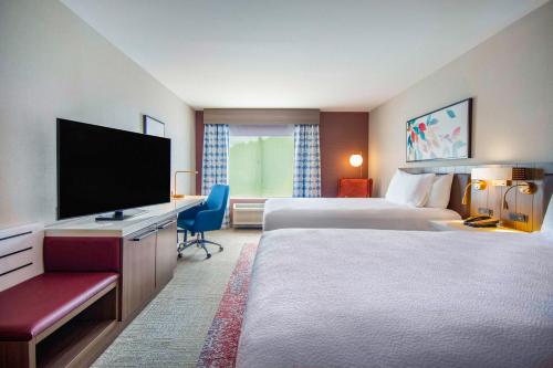 a hotel room with two beds and a flat screen tv at Hilton Garden Inn Danbury in Danbury