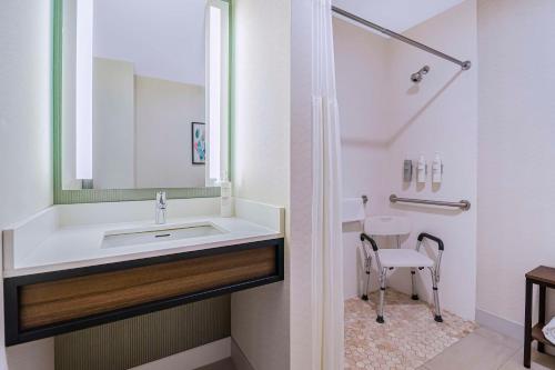a white bathroom with a sink and a chair at Hilton Garden Inn Danbury in Danbury