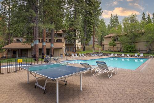 a ping pong table and chairs in front of a swimming pool at Rooted Resort in Kings Beach