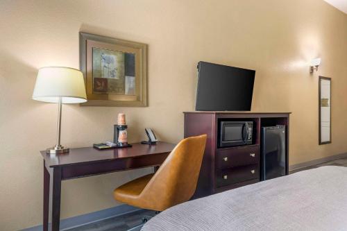 a hotel room with a desk with a television and a bed at Quality Inn and Suites Groesbeck in Groesbeck