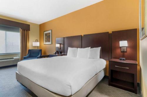 a bedroom with a large white bed and a blue chair at Comfort Inn & Suites Mexia in Mexia