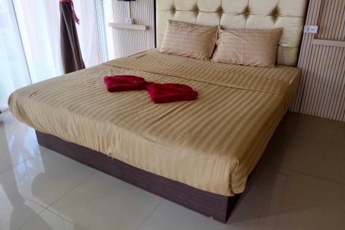 a bed with a red bow tie on it at The Resort Angel Hill in Ban Khlong Phai