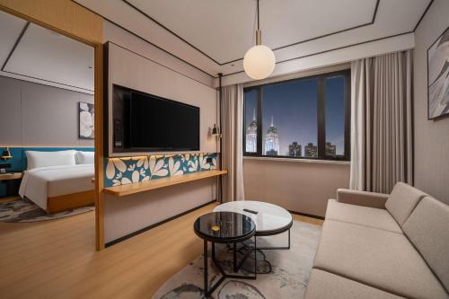 a hotel room with a bed and a television at Hilton Garden Inn Shanghai Caoyang in Shanghai